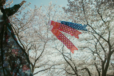 Midsection of woman holding windsock while standing against trees