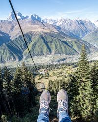 Human legs on cable railway above mountains 