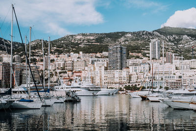 Sailboats moored in harbor against buildings in city