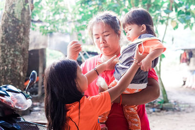 Girl taking sister carried by mother