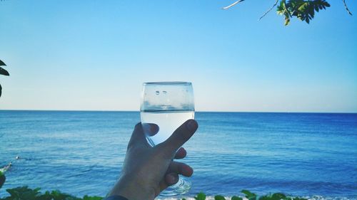 Close-up of hand holding sea against clear sky