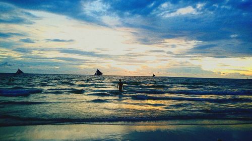 Silhouette people on beach against sky during sunset