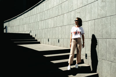 Full length of young woman standing against wall