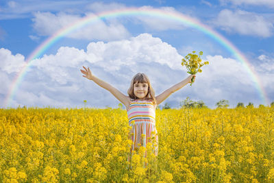 Portrait of cute girl holding flowers while standing in field