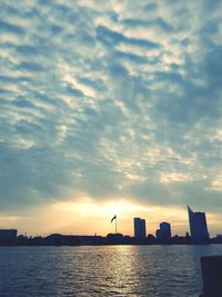 Silhouette city by sea against sky during sunset