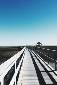 Footbridge over water against clear sky