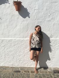 Young woman standing against wall