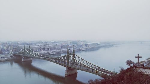 Bridge over river in city against sky