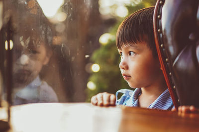 Portrait of kid stand still near window glass and looking to outside. little child reflecting.