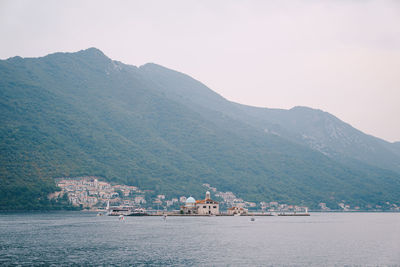 Scenic view of sea by mountain against sky