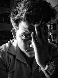 Portrait of young man covering face at home