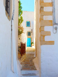 Empty greek alley with turquoise door amidst buildings