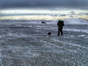 Silhouette man with dog on beach against sky