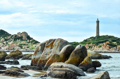 Rocks in sea against cloudy sky