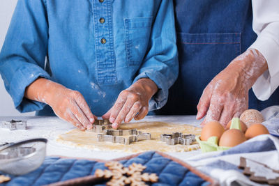 Midsection of grandmother teaching grandson cooking