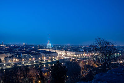 Aerial view of illuminated buildings against blue sky at night