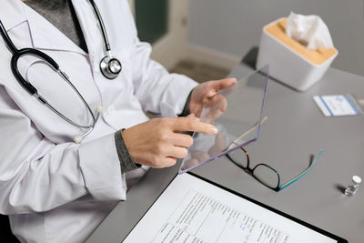 Unrecognizable female doctor touching with finger transparent tablet