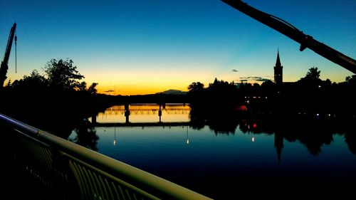 Silhouette of bridge over river at sunset