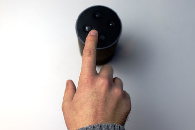 Cropped hand of person holding key against white background
