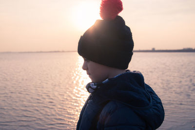 Man wearing hat against sea during sunset