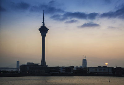 Tower in city against sky during sunset