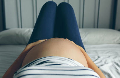 Low section of woman relaxing on bed at home