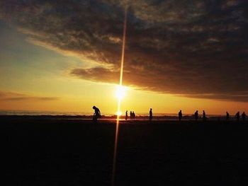 Silhouette people on beach against sky during sunset