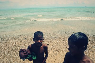 Children standing on beach against sky