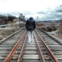 Rear view of man walking on railroad track