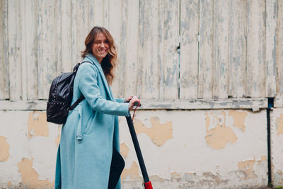 Portrait of smiling woman standing against wall