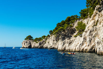 People on boat at sea against clear blue sky