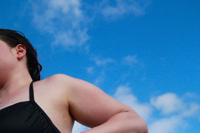 Low angle portrait of woman against blue sky