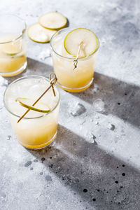 Pear cocktail or mocktail with soda and pear puree and fruit slices on gray background with shadow