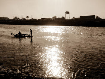 Silhouette people on river against sky