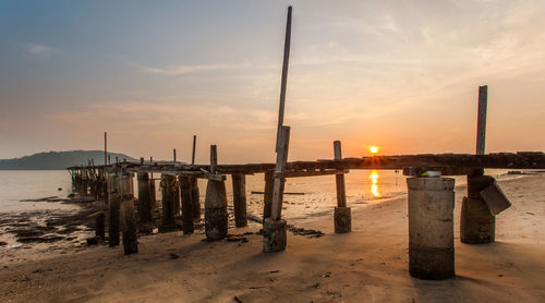 Wooden posts on beach at sunset