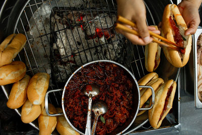 Directly above view of hands stuffing stewed pork into a banhmi in hue city night market, vietnam