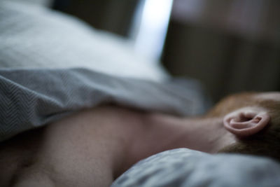 Close-up of man sleeping on bed at home
