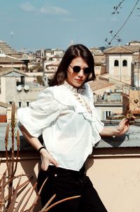 Portrait of young woman standing against buildings