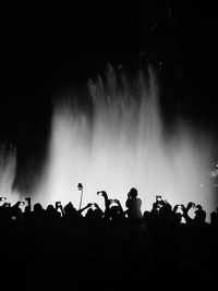 Silhouette people against fountain at night