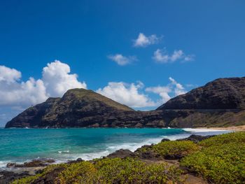 Scenic view of sea and mountains against blue sky