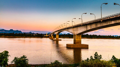 Bridge over river against sky during sunset