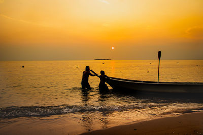 View of people on beach against sky during sunset