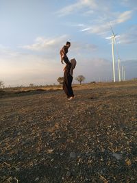 Mother picking up son while standing on land against sky
