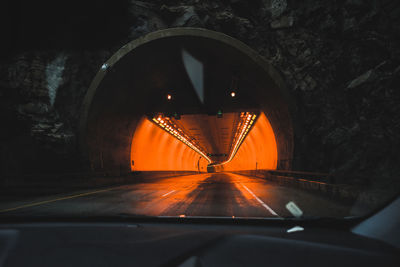 A brightly lit orange tunnel seen from the inside of a driving car