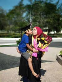 Brother kissing sister after graduation ceremony