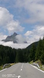 Scenic view of road by mountains against sky