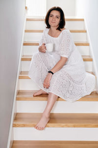 Mid age adult woman plus size sitting on stairs in the morning. romantic cozy home atmosphere. body