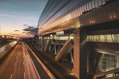 Light trails on bridge in city against sky during sunset