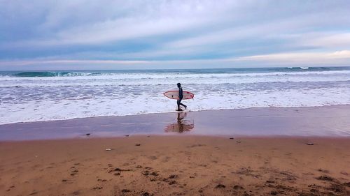 Man standing on beach against sky during sunset