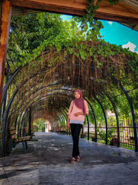 Full length portrait of woman standing against trees